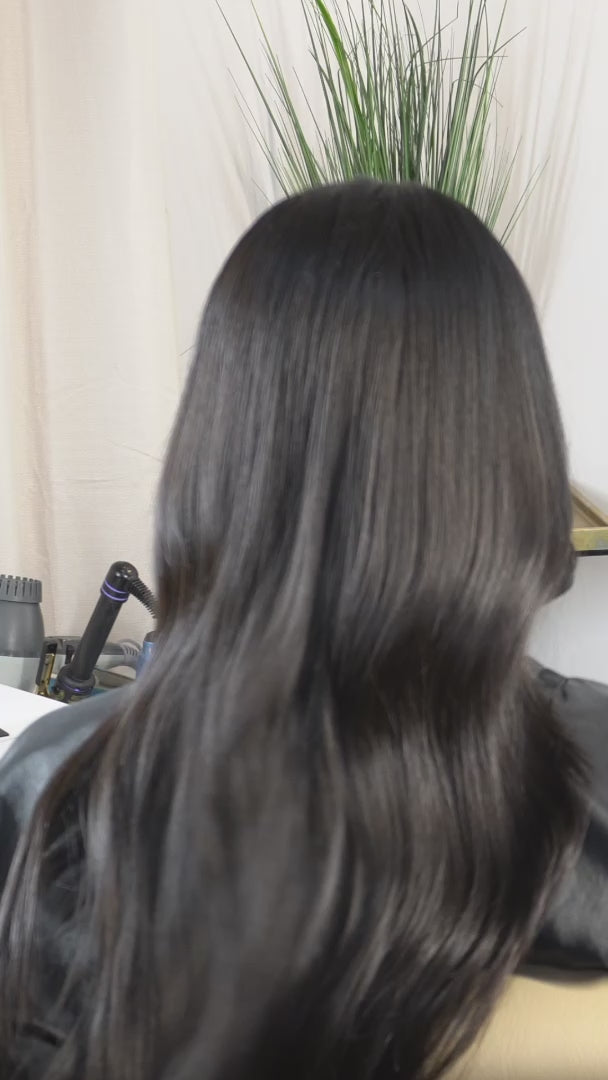 Load video: Video showing Ascension Extensions' ethically sourced Raw Indian Wavy human hair being colored from its natural brown shade to black, highlighting the hair's natural wave pattern, texture, luster, and movement.